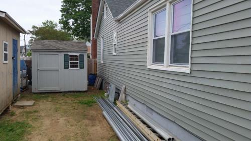 8x8 gray utility gable, 40 inch door, 1 window, green shutters, weathered wood roof